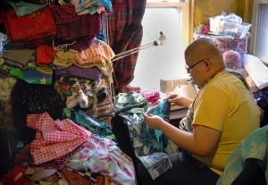 Eugene Tan, who performs regularly at Jacque's drag show and cabaret, works on a costume beside a pile of unused fabric.  Tan said that every time a fabric store has a sale, he ends up purchasing another bolt or two. (Blast staff photo/Adam J. Sell)