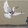 One of Banksyâ€™s contribution to the wall dividing Israel and Palestine
