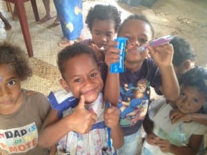 Fijian children in the village of Kanacea gather around to get donated toothbrushes and learn how to clean their teeth. 